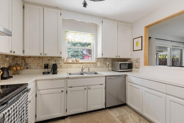 kitchen featuring a sink, decorative backsplash, appliances with stainless steel finishes, and white cabinetry