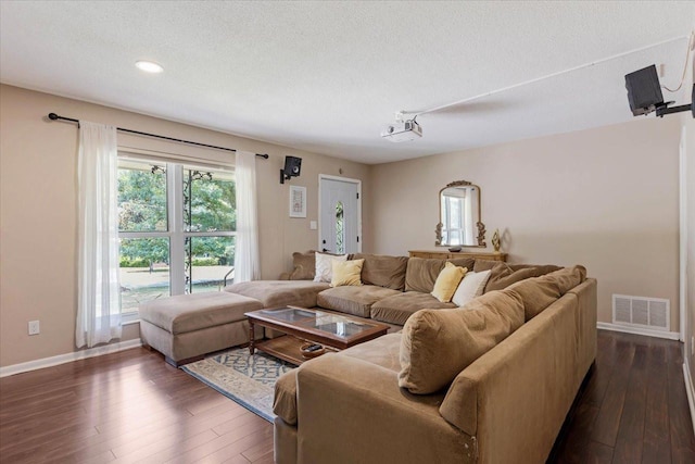 living area featuring visible vents, baseboards, dark wood-type flooring, and a textured ceiling