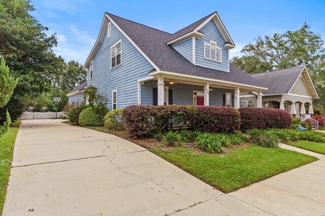 view of front of house featuring a shingled roof, fence, and a porch