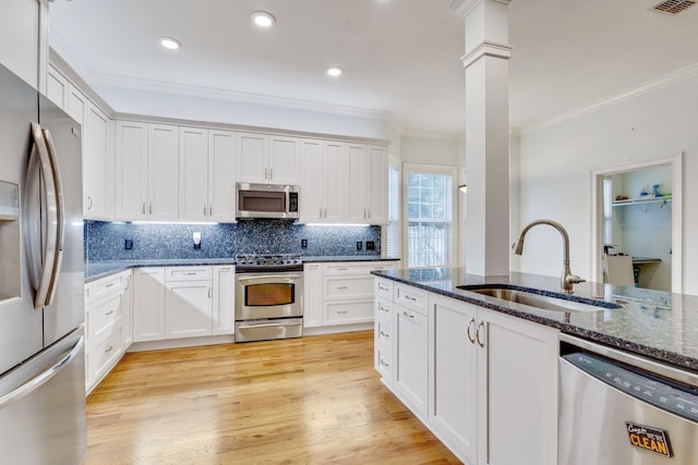 kitchen featuring white cabinets, dark stone counters, stainless steel appliances, and a sink