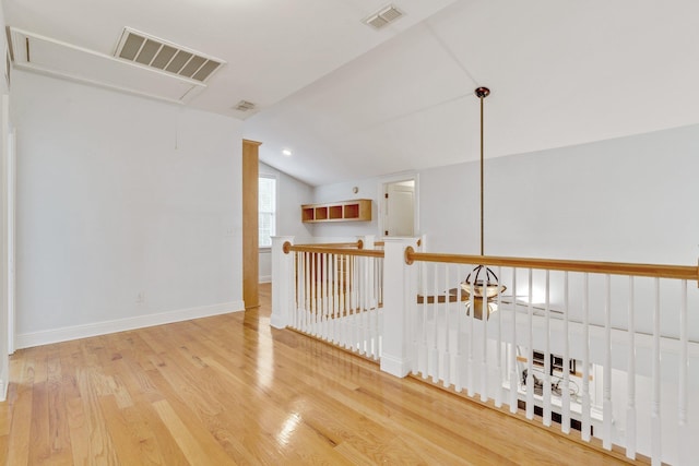 corridor featuring attic access, lofted ceiling, visible vents, and wood finished floors