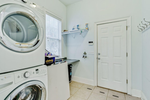 laundry room featuring stacked washer and dryer, laundry area, baseboards, and light tile patterned floors