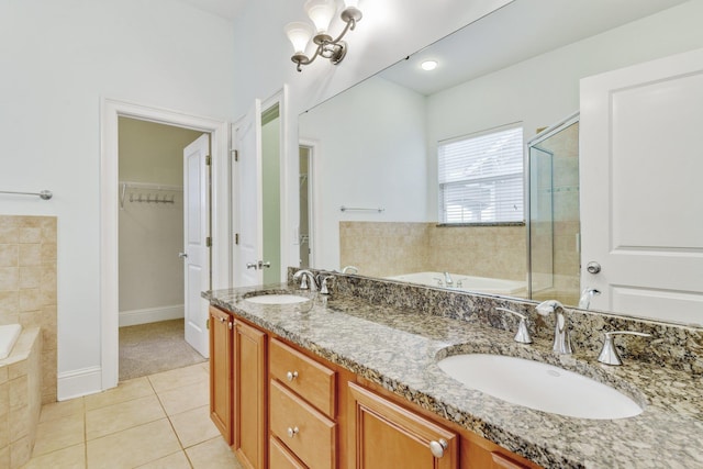 bathroom featuring a garden tub, a sink, a spacious closet, and tile patterned floors