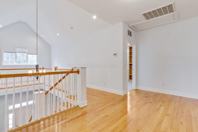 unfurnished room with baseboards, wood finished floors, visible vents, and attic access