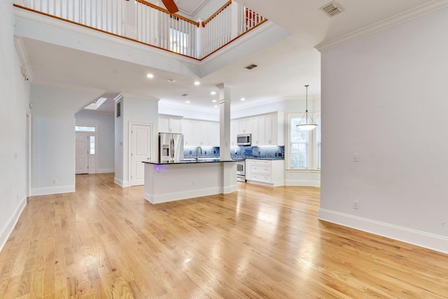living room featuring ceiling fan, light wood-style flooring, visible vents, a wealth of natural light, and crown molding