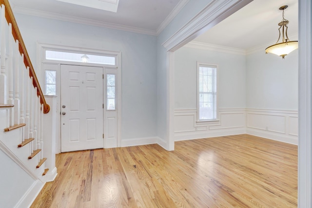 foyer featuring light wood-style floors, stairway, and crown molding
