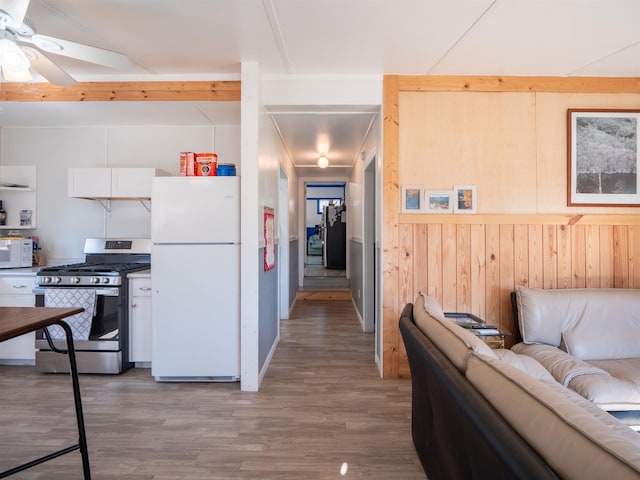 kitchen featuring light wood-style flooring, white appliances, a ceiling fan, white cabinetry, and open floor plan