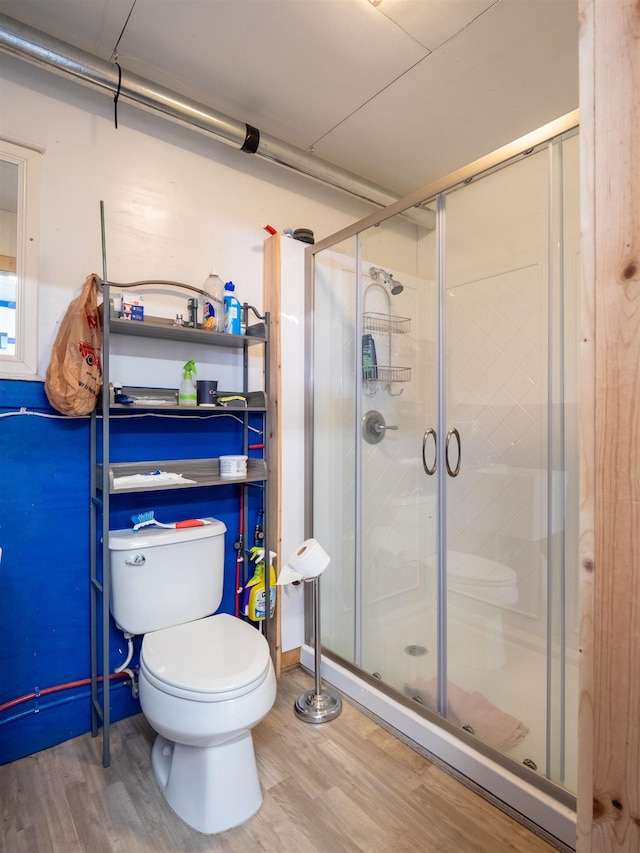 bathroom with wood finished floors, toilet, and a shower stall