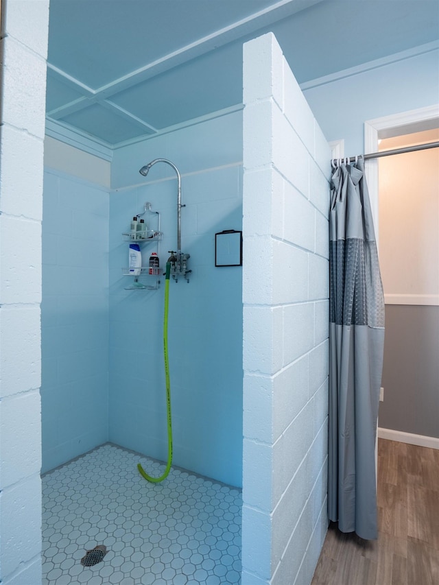 full bathroom with a tile shower and wood finished floors