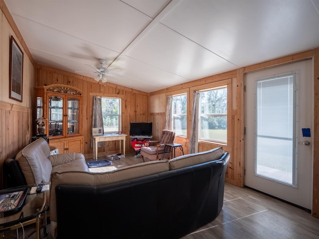 living room featuring lofted ceiling, ceiling fan, and wooden walls