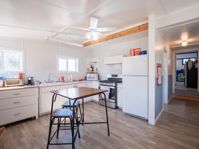 kitchen with white appliances, a sink, light wood-style flooring, and white cabinets