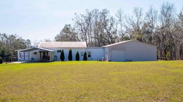 rear view of property with a garage, metal roof, a lawn, and an outdoor structure