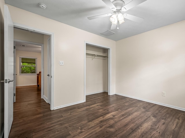 unfurnished bedroom featuring a closet, ceiling fan, visible vents, baseboards, and dark wood finished floors