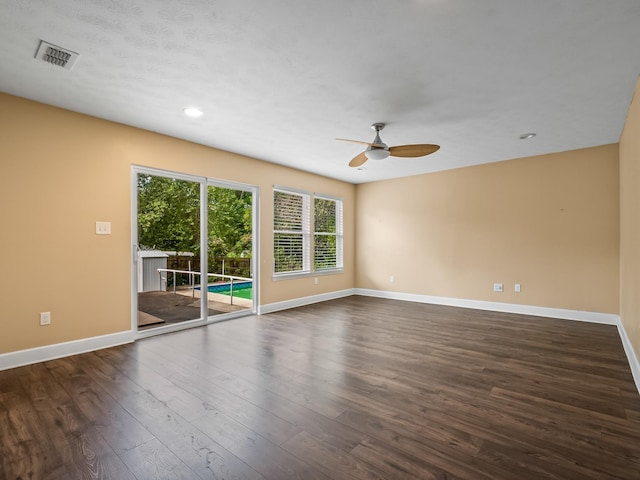 unfurnished room featuring baseboards, visible vents, a ceiling fan, and dark wood finished floors