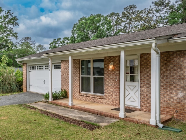 view of front of property featuring aphalt driveway, roof with shingles, an attached garage, a porch, and brick siding
