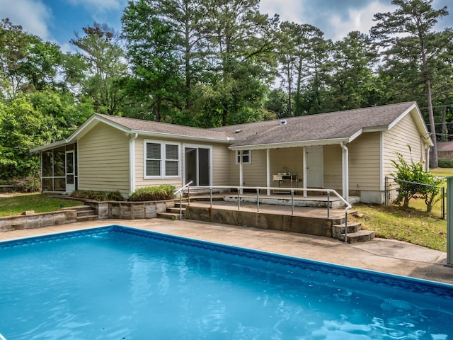 pool with fence, a patio area, and a sunroom
