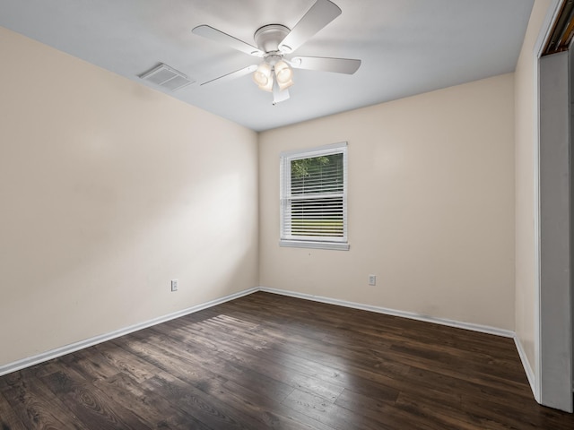 empty room with dark wood-style floors, visible vents, and baseboards