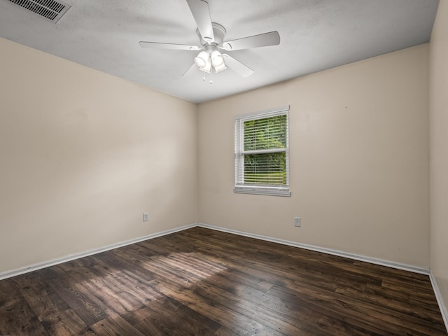spare room featuring dark wood-type flooring, visible vents, ceiling fan, and baseboards
