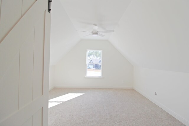 additional living space with a barn door, ceiling fan, light carpet, and lofted ceiling