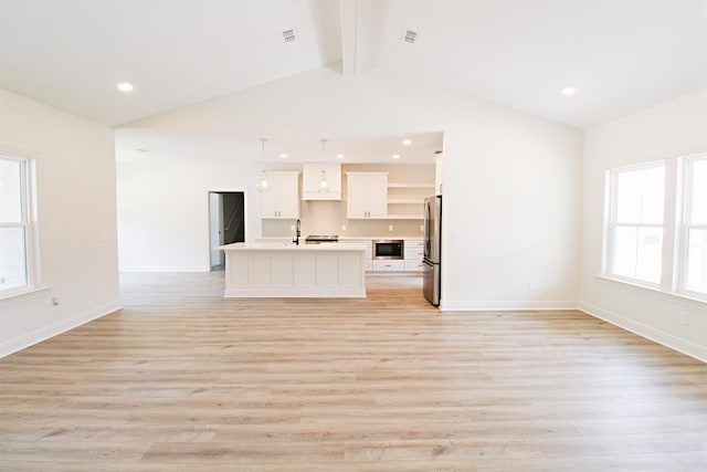 unfurnished living room with sink, light hardwood / wood-style flooring, and lofted ceiling with beams