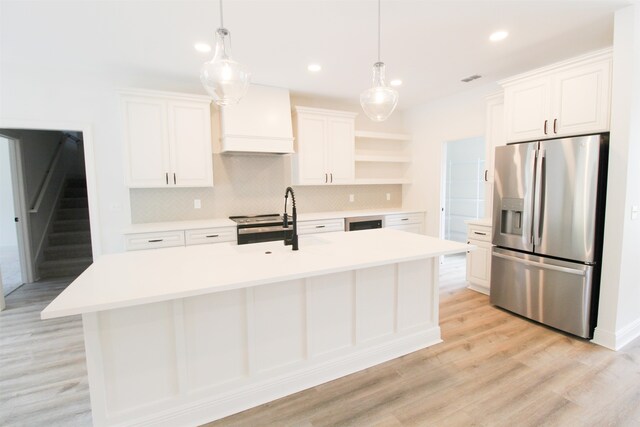 kitchen featuring stainless steel appliances, white cabinetry, a center island with sink, and light wood-type flooring