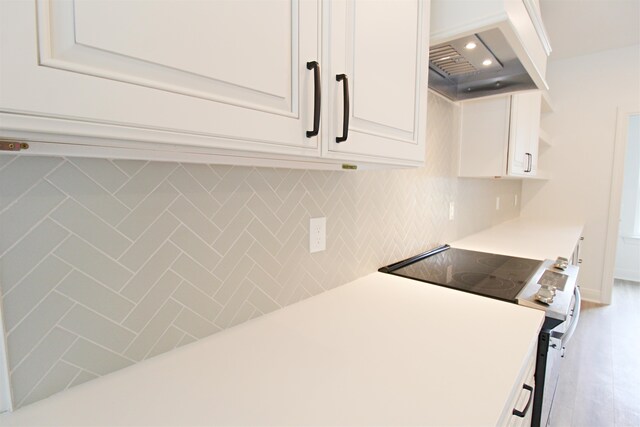 kitchen featuring range with electric stovetop, premium range hood, and white cabinets