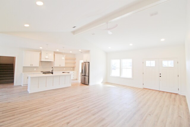 unfurnished living room featuring light hardwood / wood-style floors, vaulted ceiling with beams, and sink