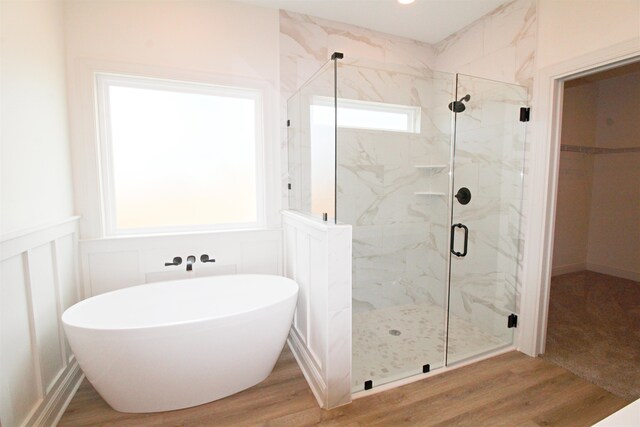 bathroom with hardwood / wood-style floors and independent shower and bath