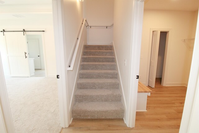 stairway with a barn door and hardwood / wood-style flooring