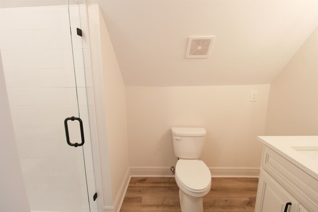 bathroom with vanity, vaulted ceiling, hardwood / wood-style flooring, toilet, and a shower with shower door