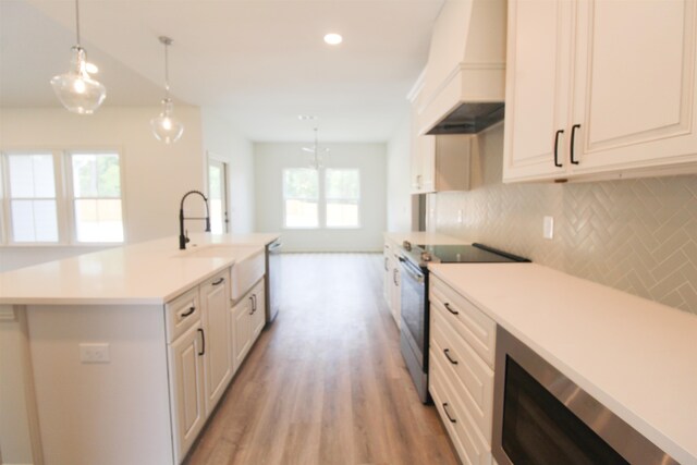 kitchen with pendant lighting, appliances with stainless steel finishes, custom range hood, and plenty of natural light