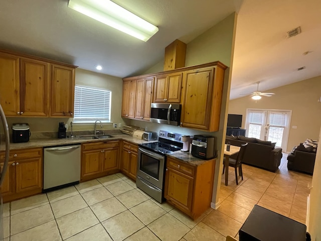 kitchen featuring stainless steel appliances, vaulted ceiling, sink, and light tile patterned floors