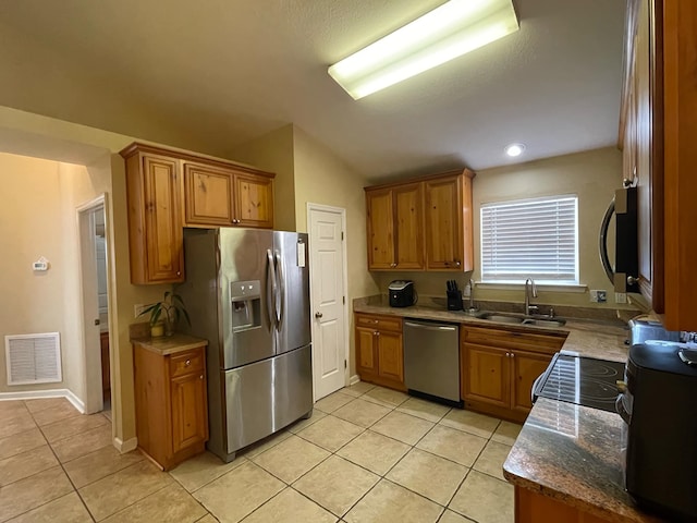 kitchen featuring light tile patterned flooring, vaulted ceiling, sink, dark stone counters, and stainless steel appliances