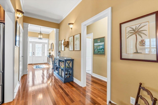 interior space with decorative columns, wood-type flooring, and crown molding