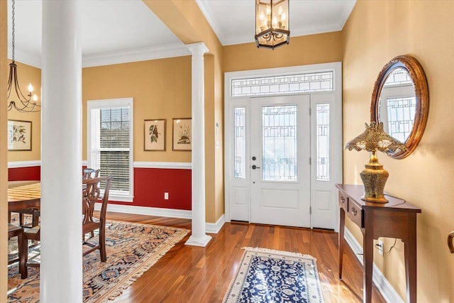 foyer featuring ornate columns, a healthy amount of sunlight, hardwood / wood-style flooring, and an inviting chandelier