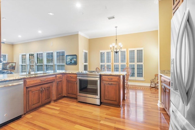 kitchen featuring sink, ornamental molding, appliances with stainless steel finishes, pendant lighting, and light hardwood / wood-style floors