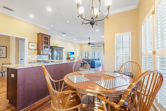 dining space with ceiling fan with notable chandelier, ornamental molding, and dark hardwood / wood-style floors