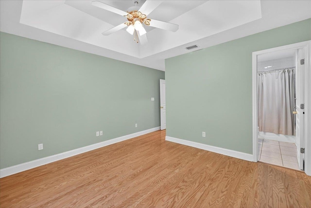 1913 Celtic Rd, Tallahassee, FL 32317 - unfurnished bedroom featuring a tray ceiling, light wood-type flooring, baseboards, and ceiling fan