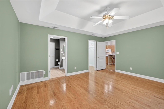 1913 Celtic Rd, Tallahassee, FL 32317 - unfurnished bedroom with a tray ceiling, a spacious closet, light wood-style flooring, baseboards, and connected bathroom