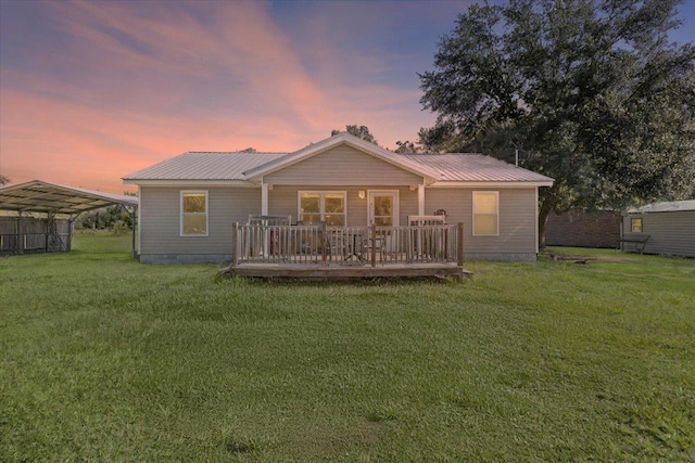1439 W Lyman Hendry Rd, Perry, FL 32347 - back of house at dusk featuring a lawn, a wooden deck, a carport, and a metal roof