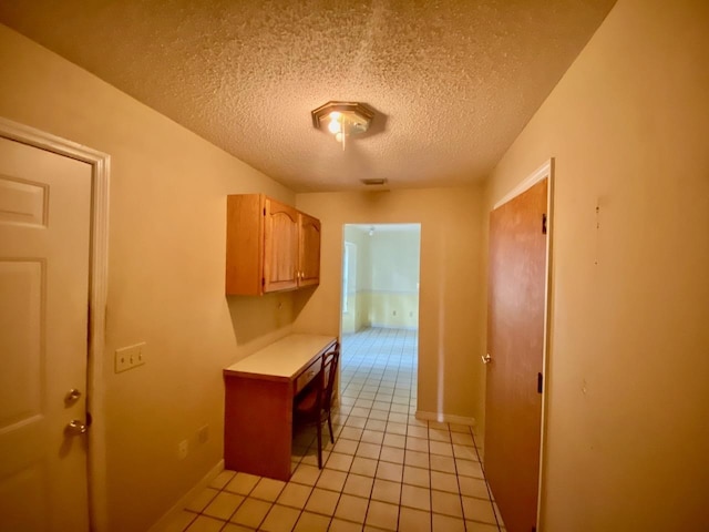 interior space featuring light tile patterned floors, baseboards, light countertops, and a textured ceiling