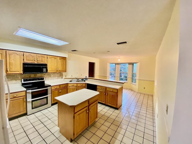 kitchen featuring light tile patterned floors, a peninsula, light countertops, a center island, and black appliances