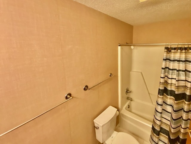 bathroom featuring toilet, shower / bath combo with shower curtain, and a textured ceiling