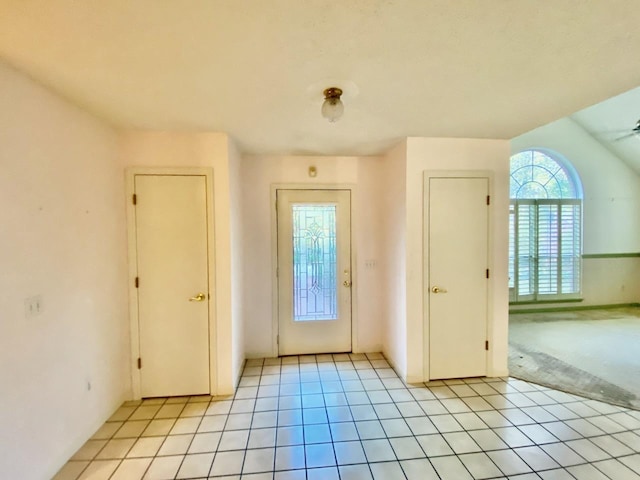 doorway to outside with light tile patterned floors and light colored carpet