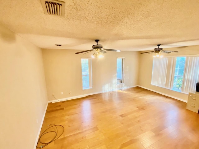 spare room with a healthy amount of sunlight, baseboards, visible vents, and wood finished floors