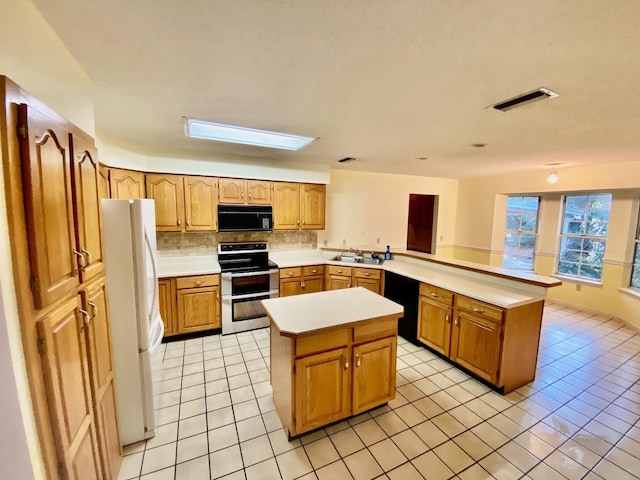 kitchen featuring a center island, light countertops, decorative backsplash, a peninsula, and black appliances