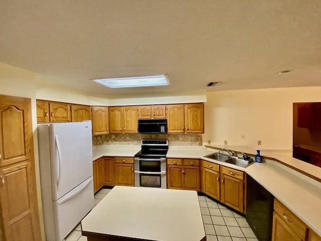 kitchen with visible vents, brown cabinetry, light countertops, black appliances, and a sink