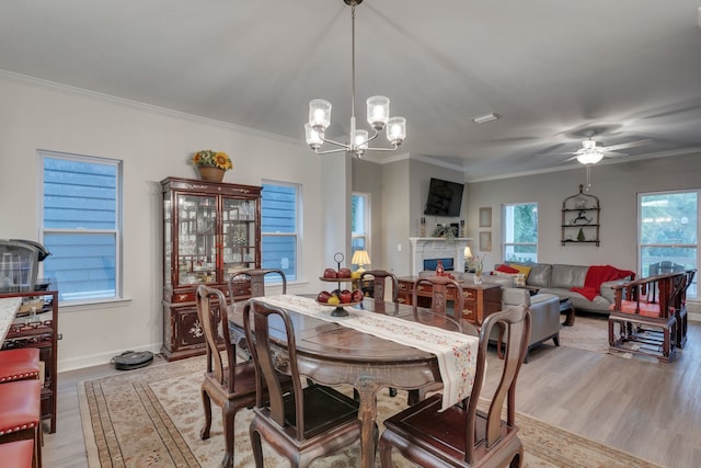 624 W 7th Ave, Tallahassee, FL 32303 - dining space with light wood-type flooring, a chandelier, ornamental molding, ceiling fan, and a lit fireplace