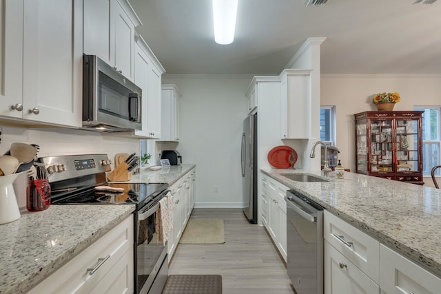 624 W 7th Ave, Tallahassee, FL 32303 - kitchen with appliances with stainless steel finishes, crown molding, white cabinetry, light wood-style floors, and light stone countertops