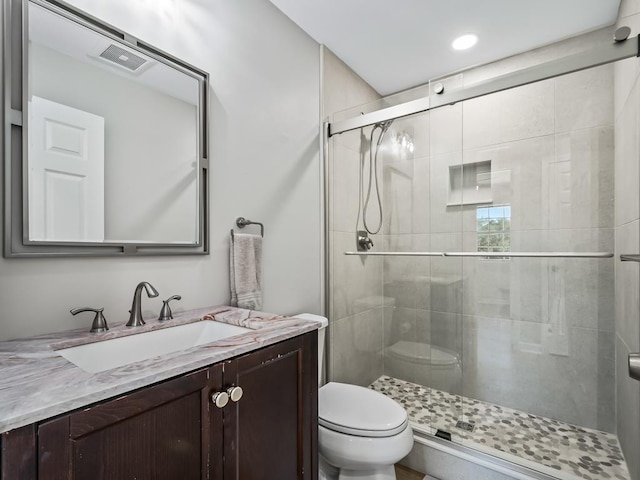 bathroom featuring vanity, toilet, and a shower with door